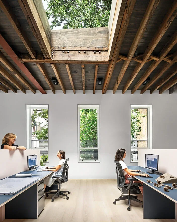 Architects at work in a daylit office beneath an open timber skylight